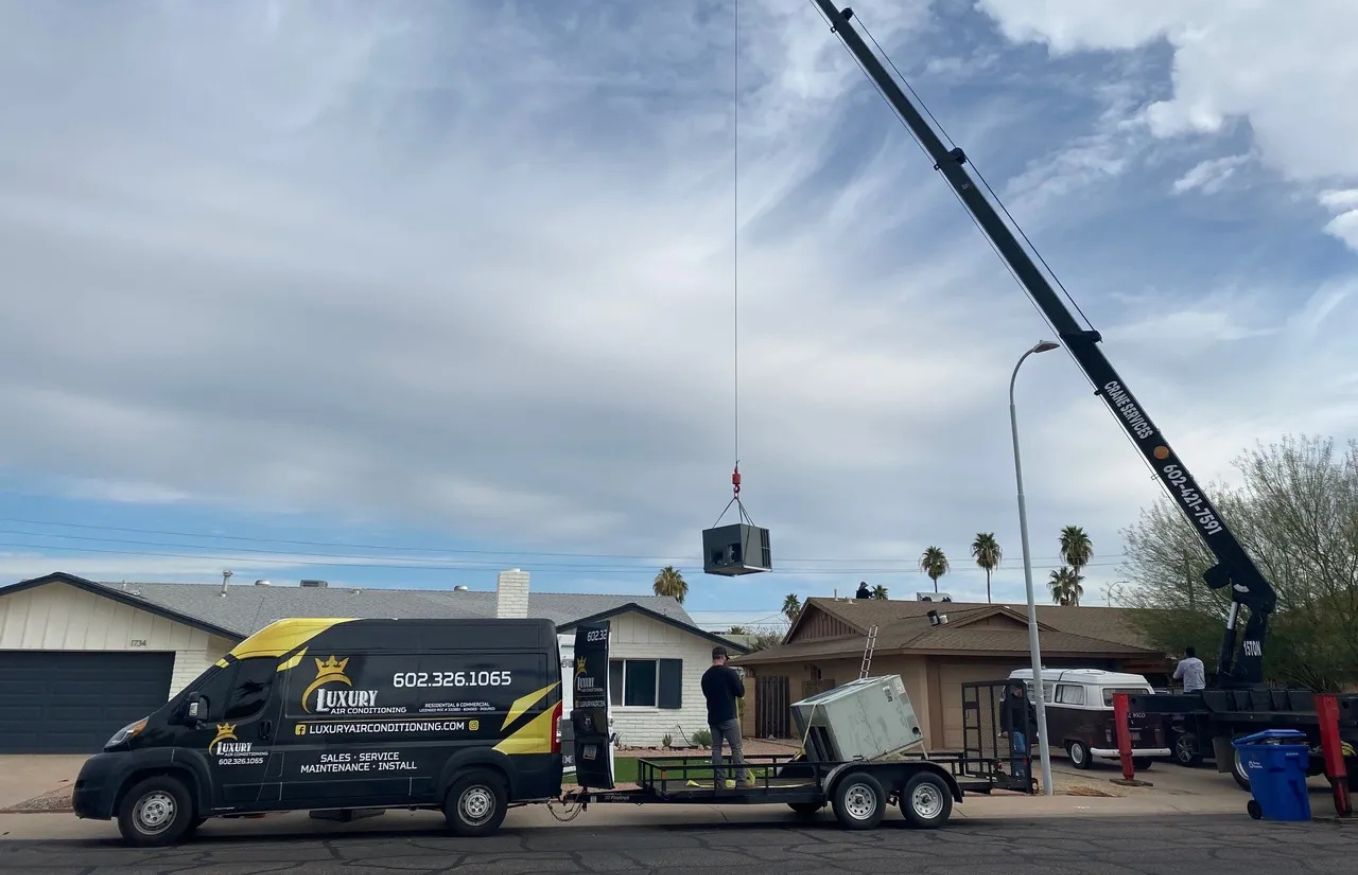 Technicians using a crane to install an air conditioning unit on a residential roof. Luxury Air Conditioning services.