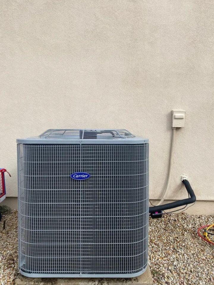 lacp-img-18 Carrier air conditioning unit installed on a gravel surface against a wall, showcasing efficient cooling capability.