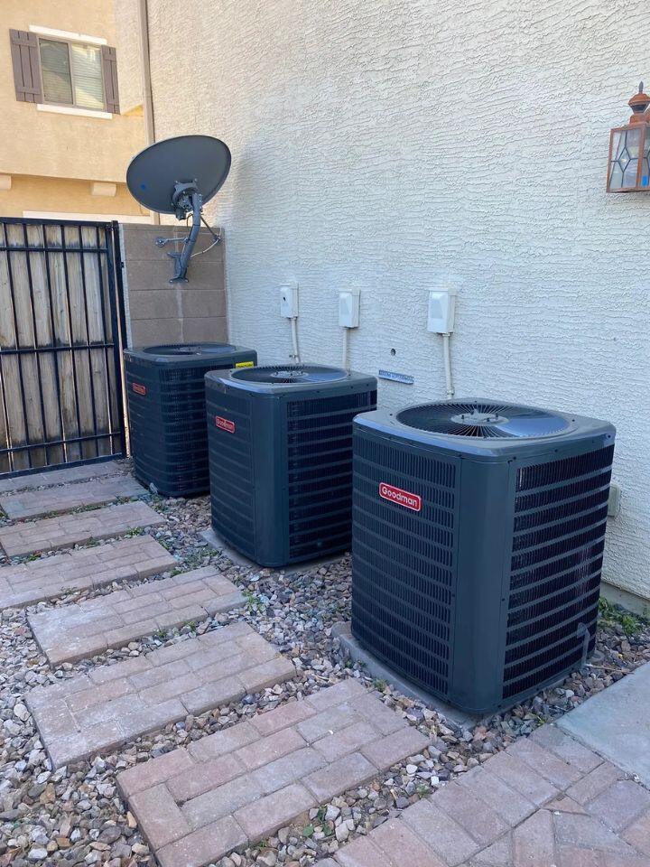 lacp-img-19 Three air conditioning units installed beside a home, with a satellite dish and stone pathway visible.