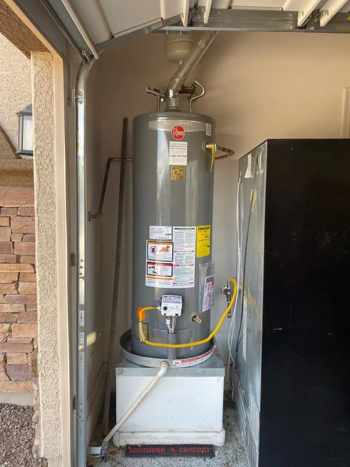 lacp-img-21 Modern gray water heater installed in a garage, featuring safety labels and connected pipes for efficient operation.