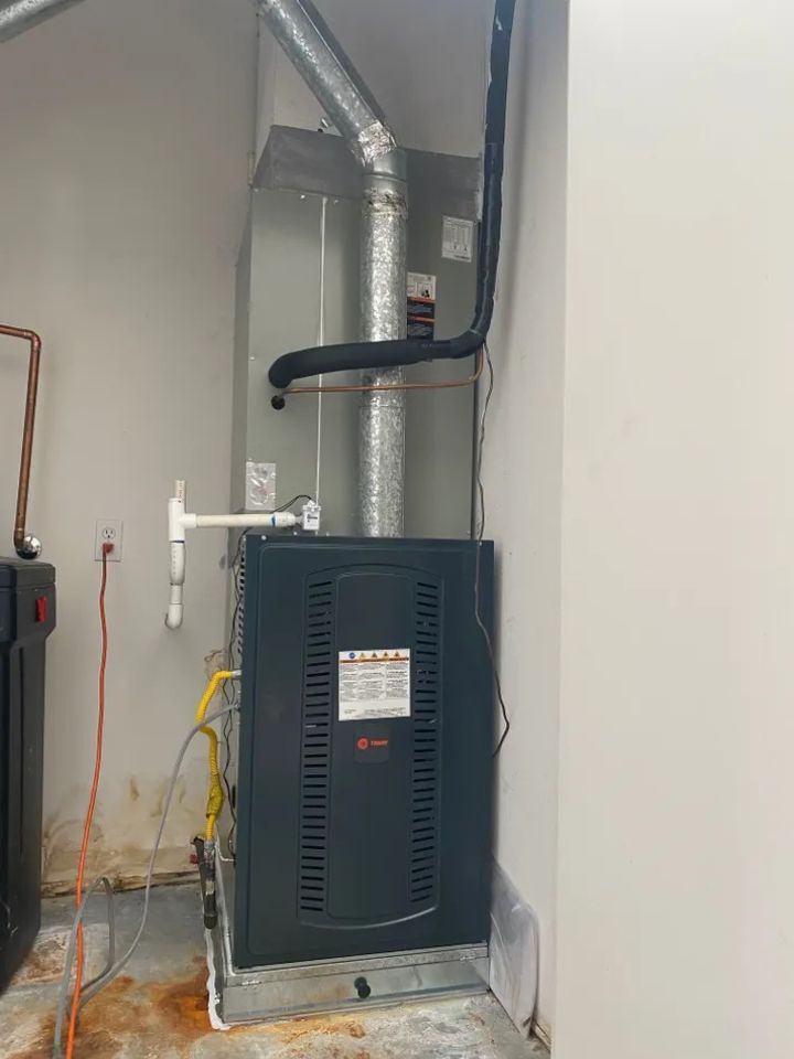 lacp-img-22 Furnace installation in a utility room with ductwork and pipes visible. Proper setup for home heating system efficiency.